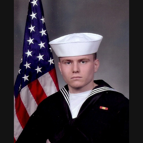 A portrait photo of Zachary Michael Dodd in his US. navy uniform with an American flag in the background