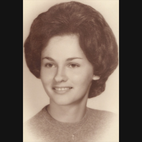 A sepia toned headshot photo of Joanie A. Dodd formerly Strnad smiling into the distance