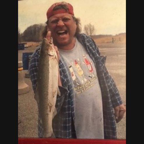 A photo of Michael A. Markiewicz excitedly holding up a fish he caught on a summer's day