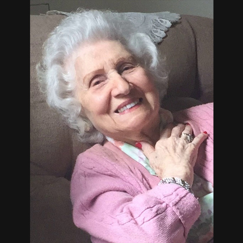 A close-up photo of Marie Thompson Roberts formerly Bove smiling brightly for the camera while resting on the couch