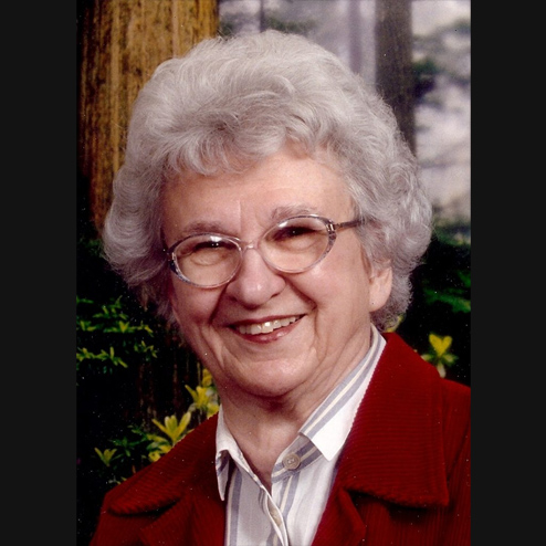 A professional portrait photo of Velma C. Kirincic with a big smile and forestry background