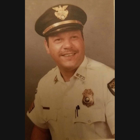 Richard M. Gamber smiling and posing for a photo in his police uniform