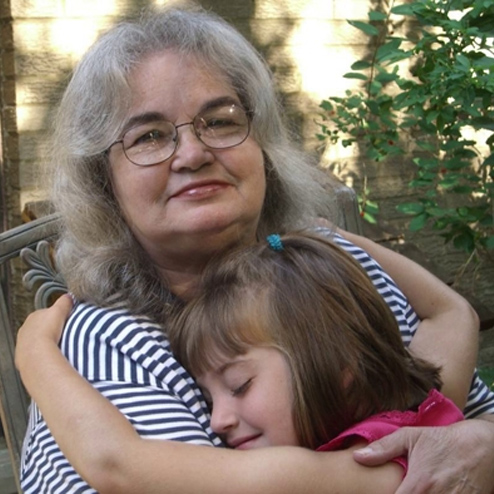 A precious photo of Marilyn S. Valentine smiling and being hugged by her granddaughter