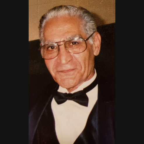 A close-up photo of Carmen A. Napoli Sr. smiling while at a black suit and tie event