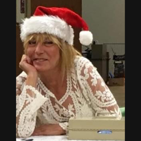 A close-up photo of Joni S. Dietz volunteering and smiling while wearing a Santa Claus hat