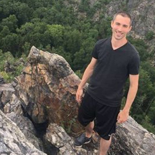 A photo of Christopher Michael Hansen posing on a rock exploring a natural area