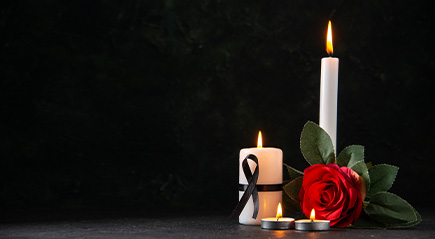 A black background with a red rose, and four candles lit