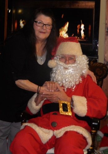 Mary Kochevar posing with Santa Claus in front of a fireplace