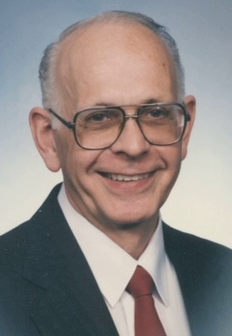 A portrait photo of Thomas "Tom" Ostrom smiling and dressed up in a suit and tie