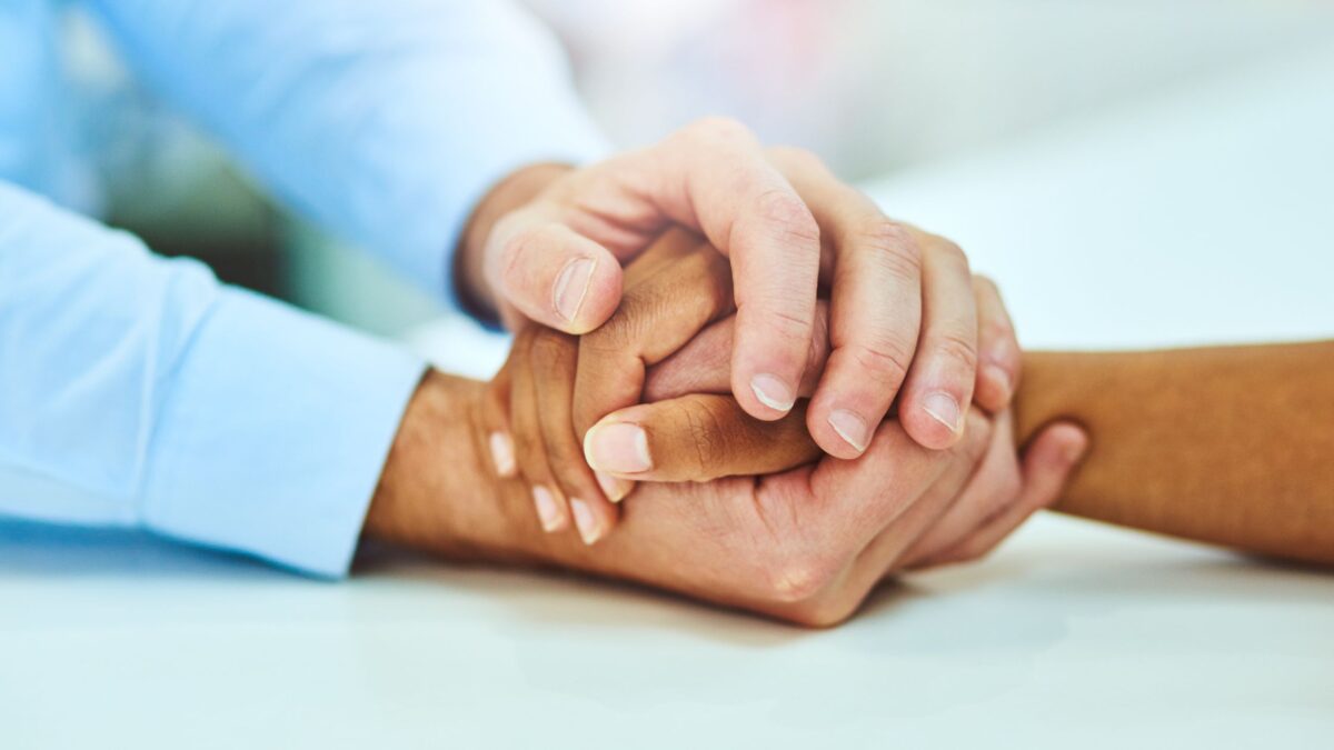 Featured image of two people holding hands and providing support for grief