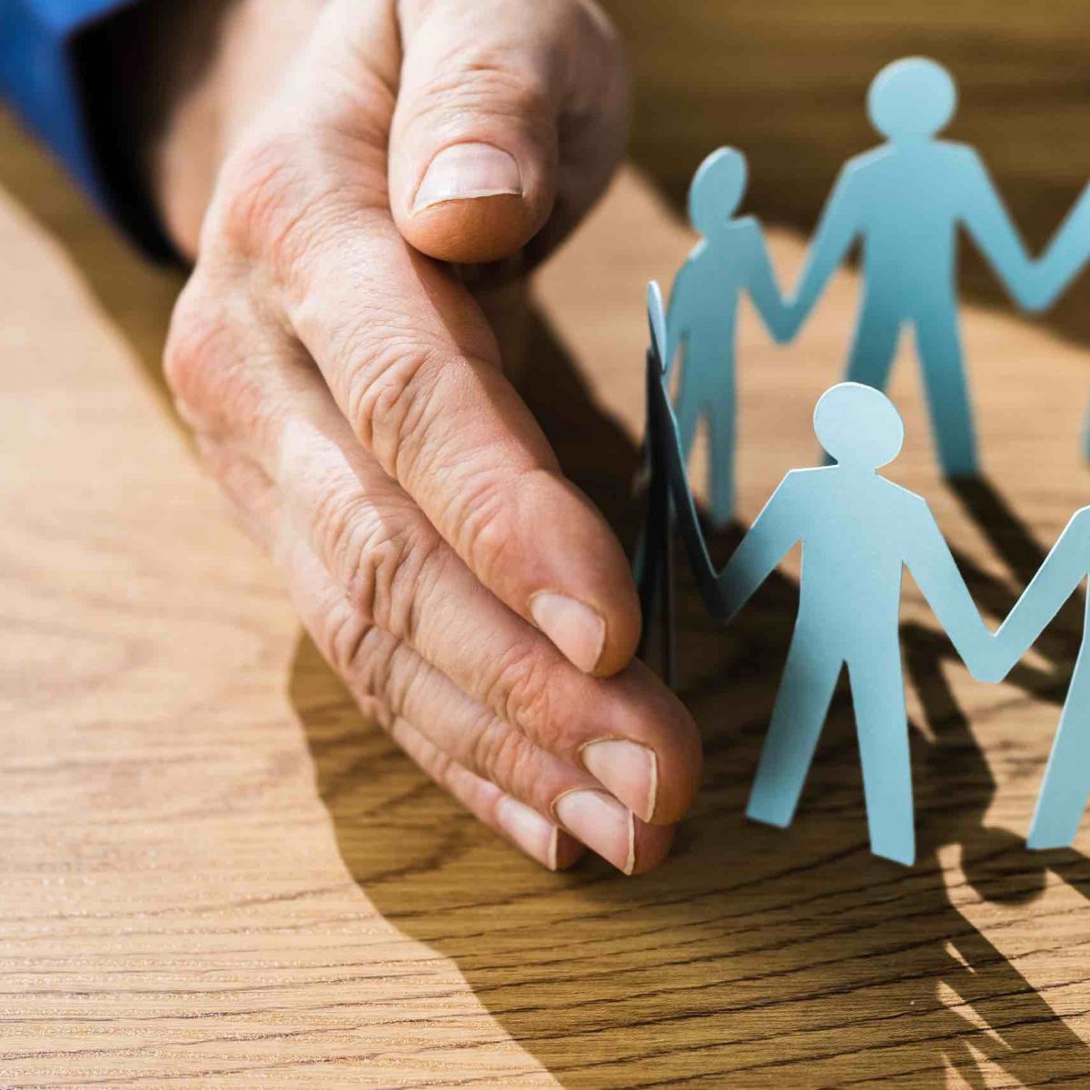 A photo of a senior gently holding a paper cut out circle of his or her family members to represent the importance of understanding burial insurance and how it can help provide financial support during times of grieving